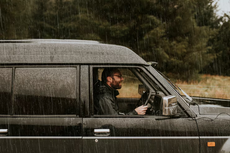 Smiling man driving his car in the rain after receiving replacement keys from a locksmith