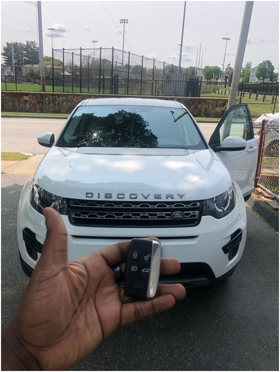 Person holding new car keys in front of a parked SUV